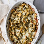 pesto tortellini with melted cheese in a baking dish