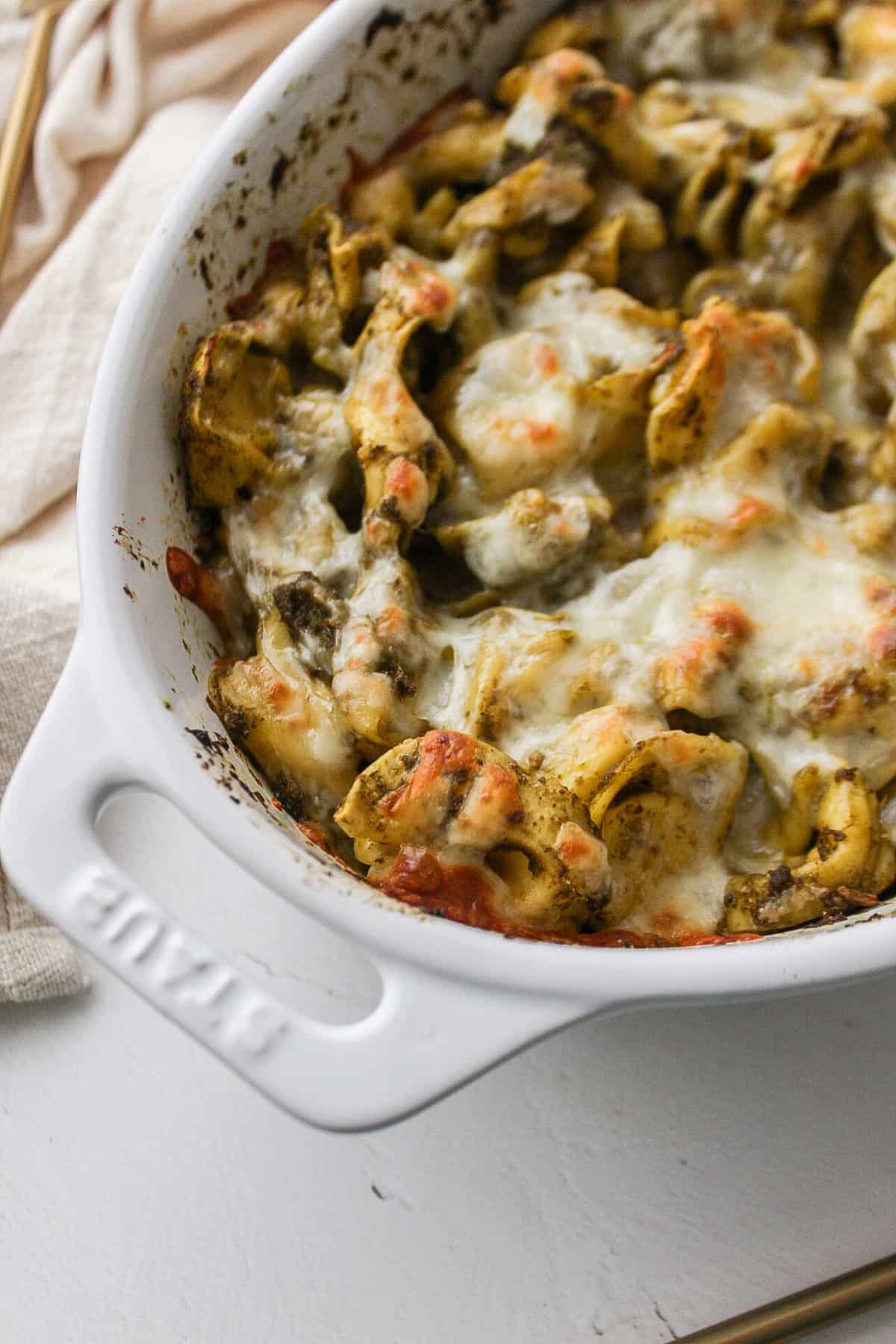 pesto tortellini with melted cheese in a baking dish