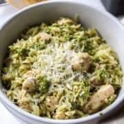 pesto orzo with chicken in a large bowl topped with parmesan cheese