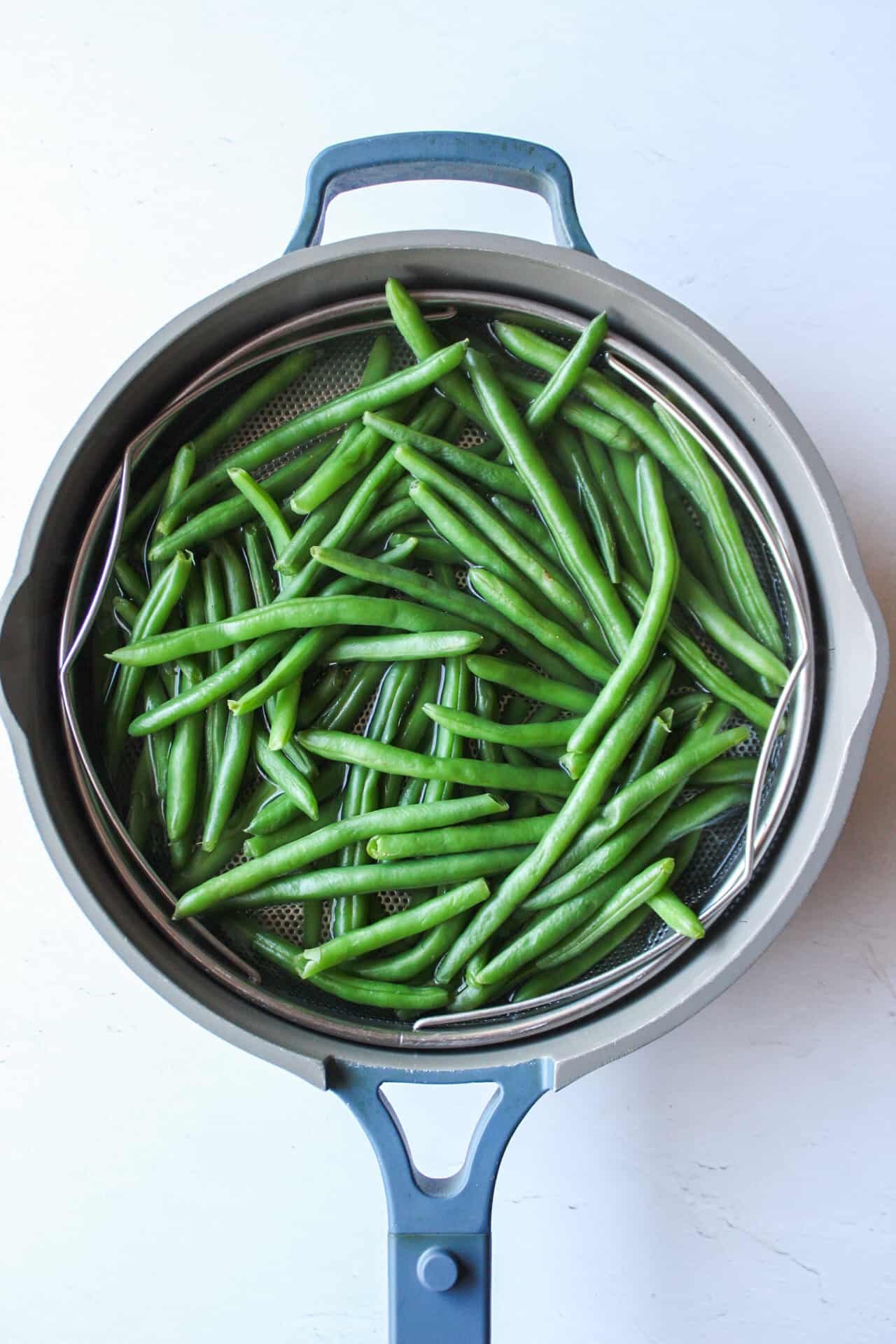 blanched green beans in a steamer colander