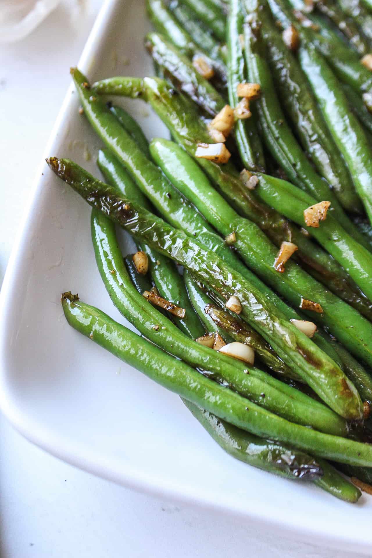 close up of green beans sautéed with garlic on a plate