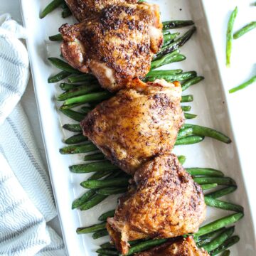 five roasted chicken thighs of a bed a sauteed string beans