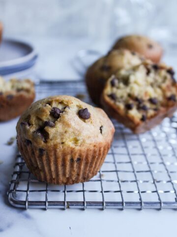 a muffin with chocolate chips in it in focus and one of them opened up
