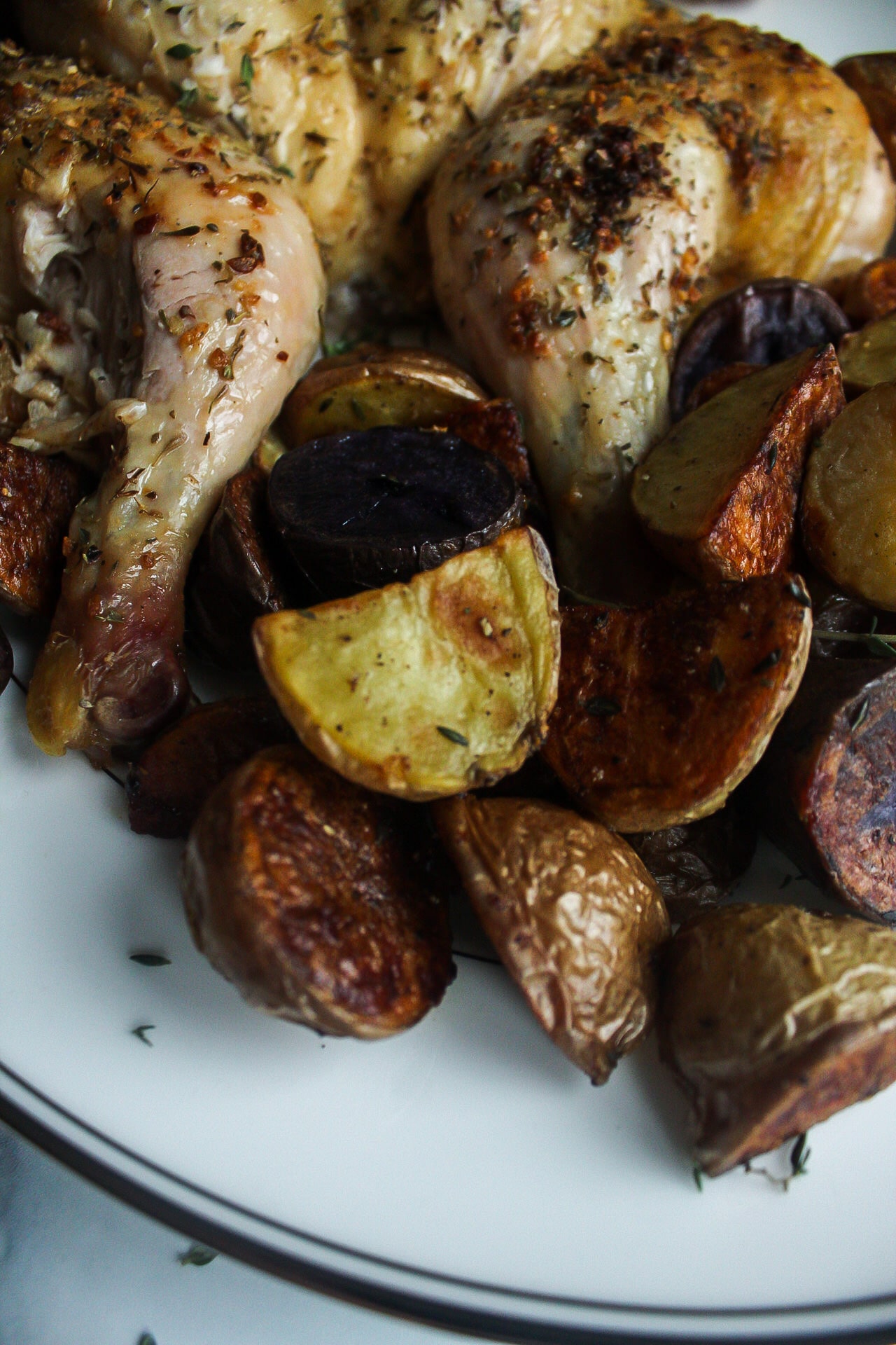 roasted potatoes with a piece of roasted chicken on a plate