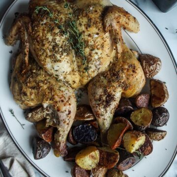 an entire whole roasted chicken with potatoes on a platter