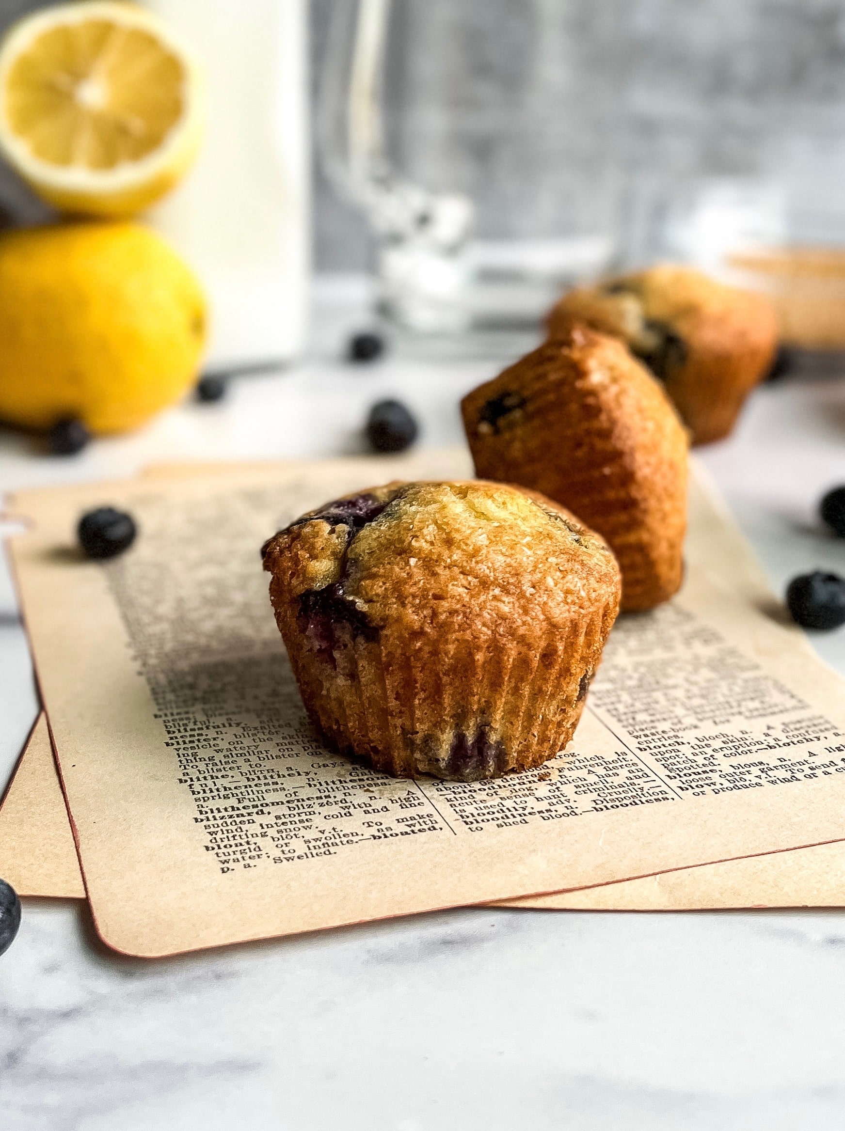 close up of muffin with lemons and blueberries in the background