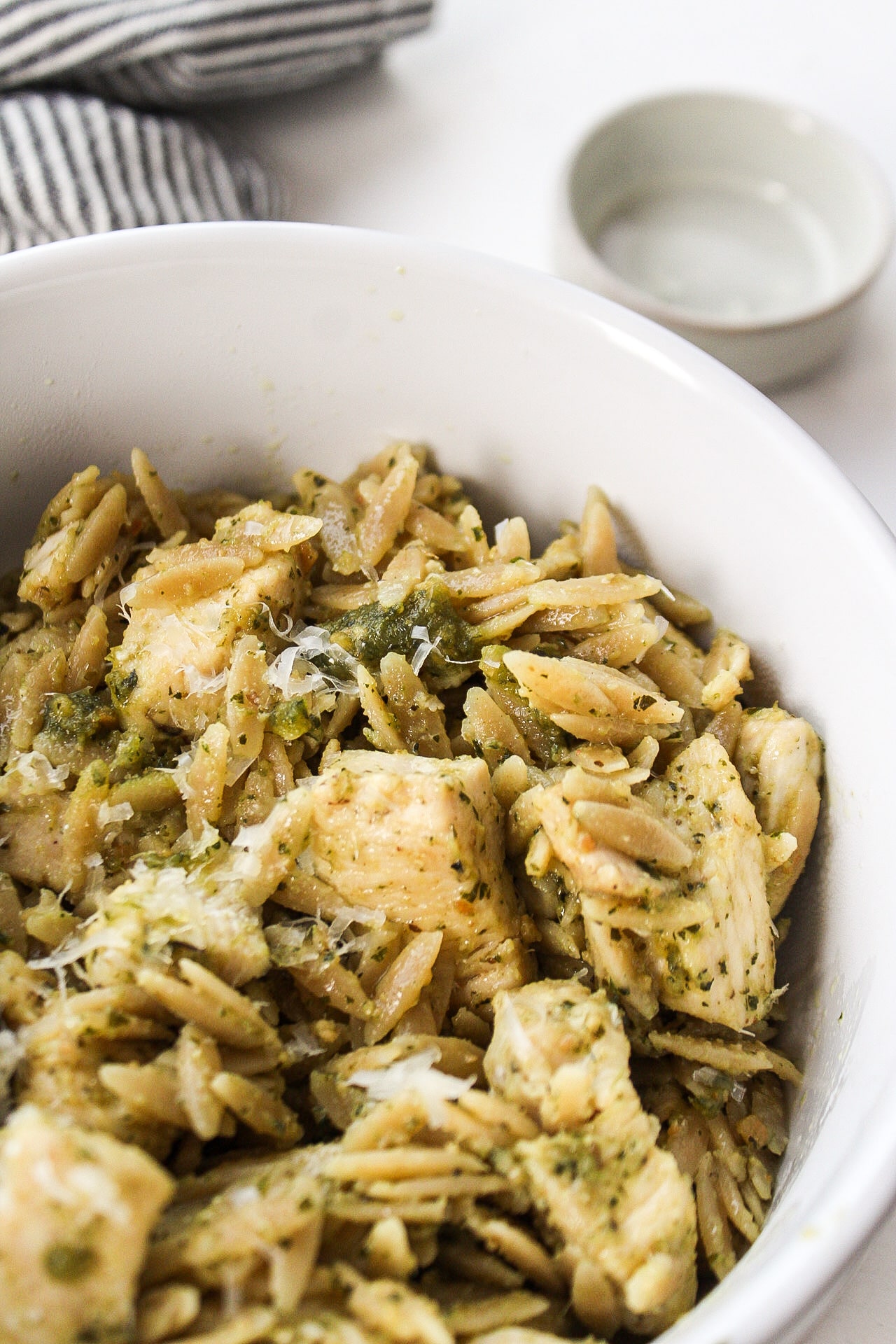 a close up photo of pesto chicken with orzo in a bowl
