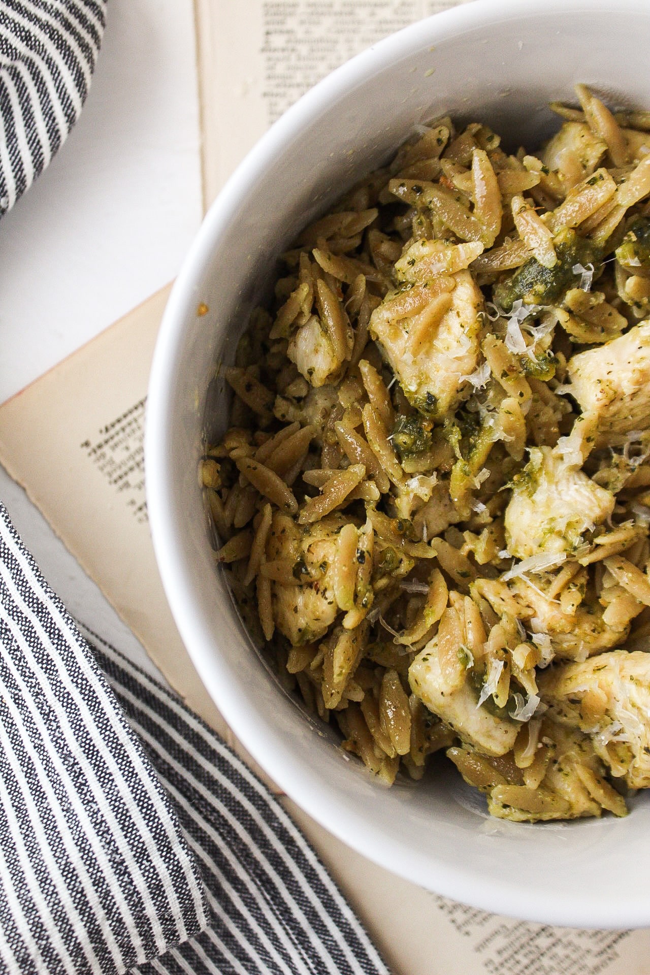 a close up of a side of a bowl with pesto orzo and chicken