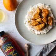 a honey bottle with a plate of chicken over rice