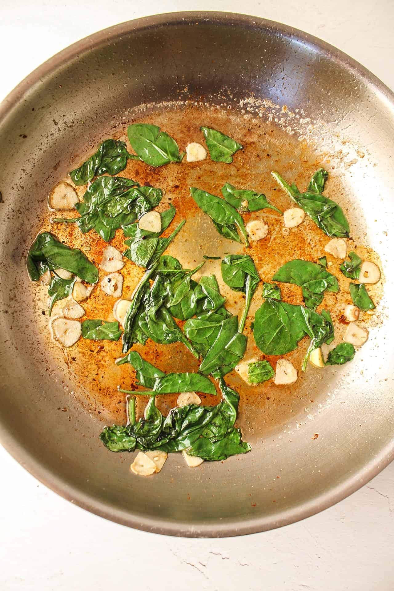 spinach and garlic sauteing in a skillet