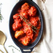 italian chicken meatballs in a casserole dish with thyme on top