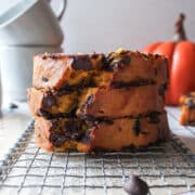 a stack of three slices of pumpkin chocolate chip bread on a cooling rack.