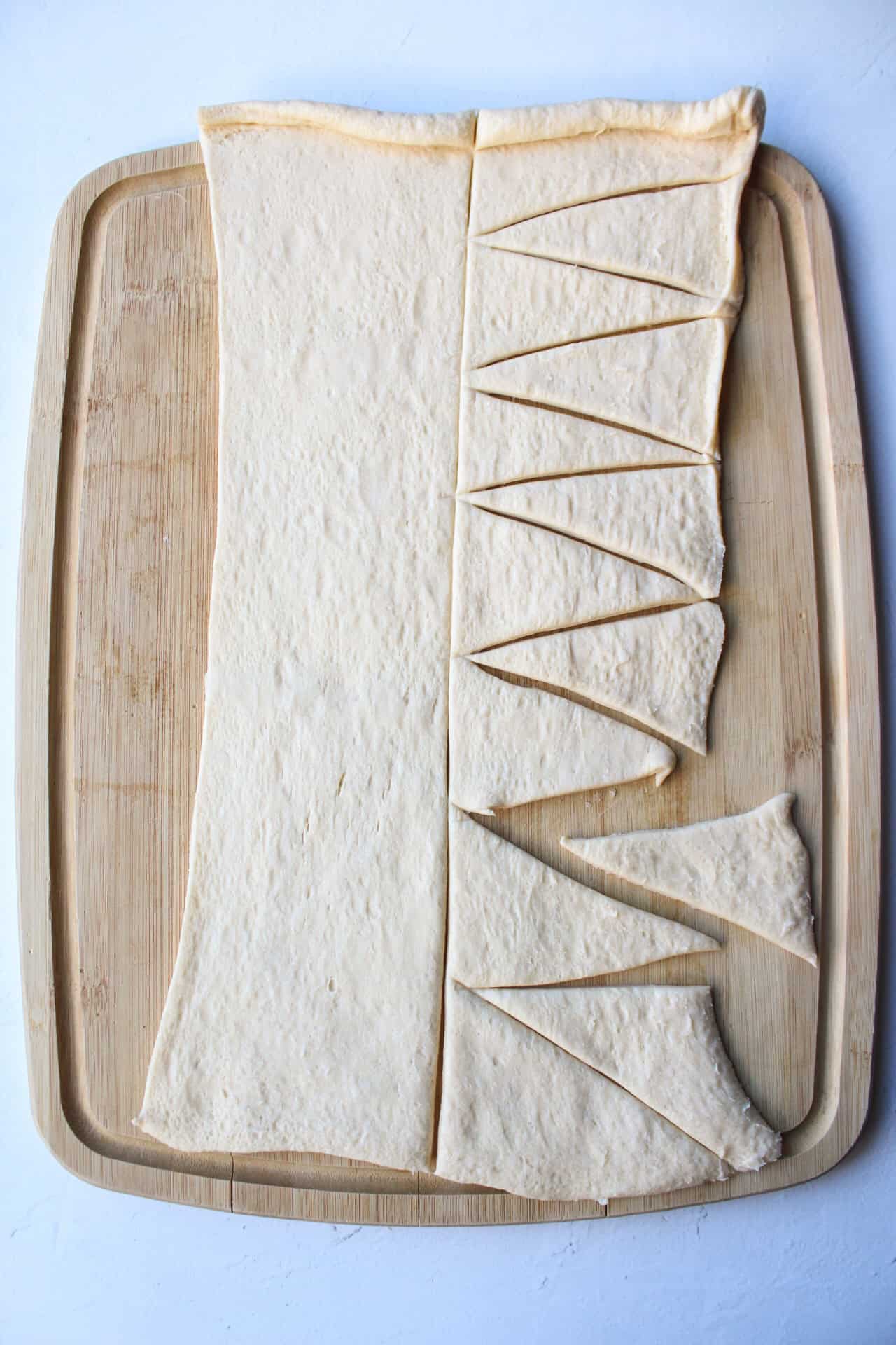 Crescent roll dough sliced into small triangles.