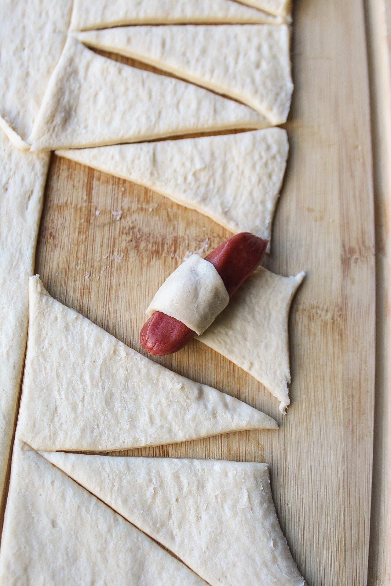 One cocktail hot dog wrapped in crescent roll dough.