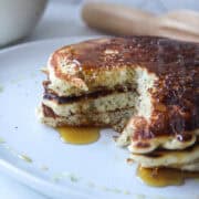 a stack of three lemon poppy seed pancakes with a portion of the pancakes cut out.