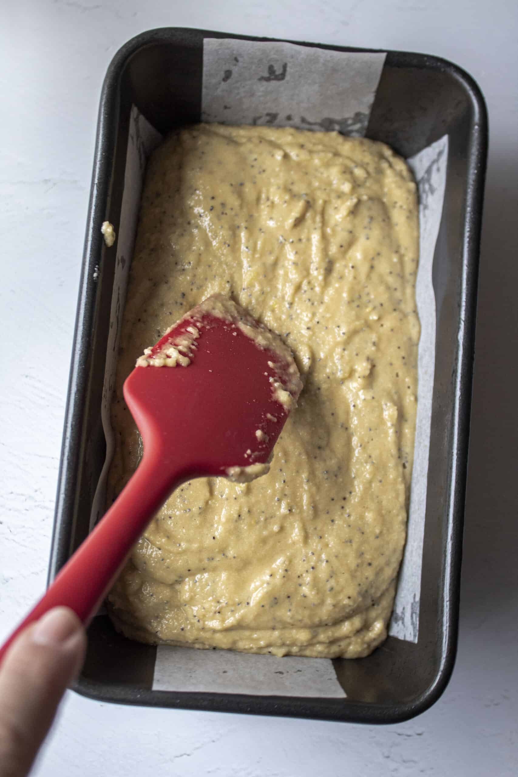 a spatula smoothing out batter in a loaf pan