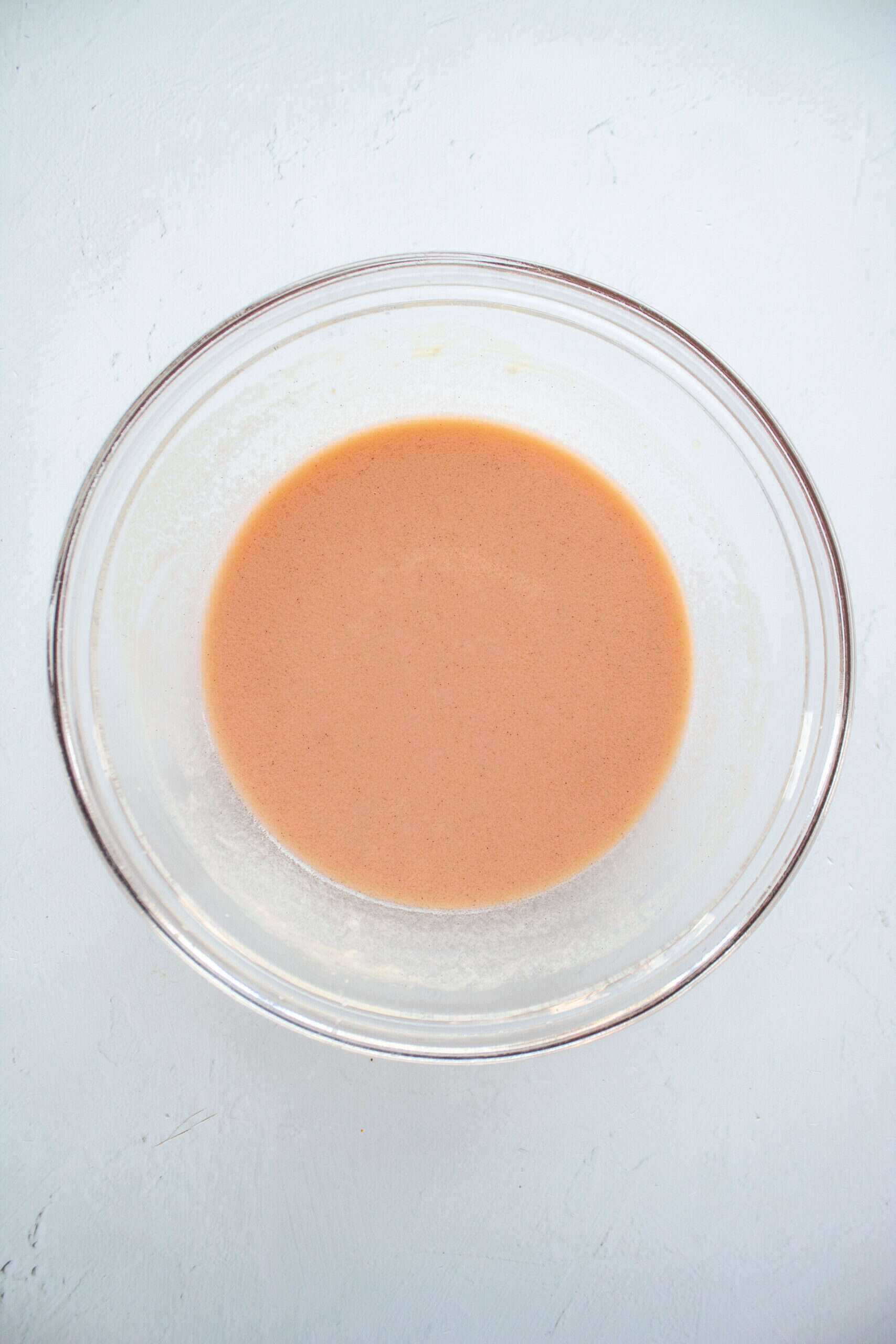 Wet ingredients for cocoa buttermilk waffles in a large bowl with added red food coloring.