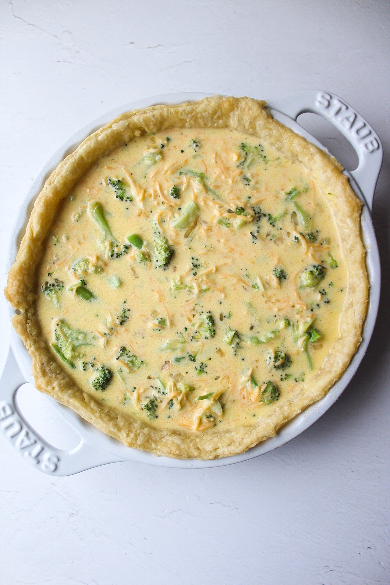 broccoli cheddar quiche in a dish unbaked