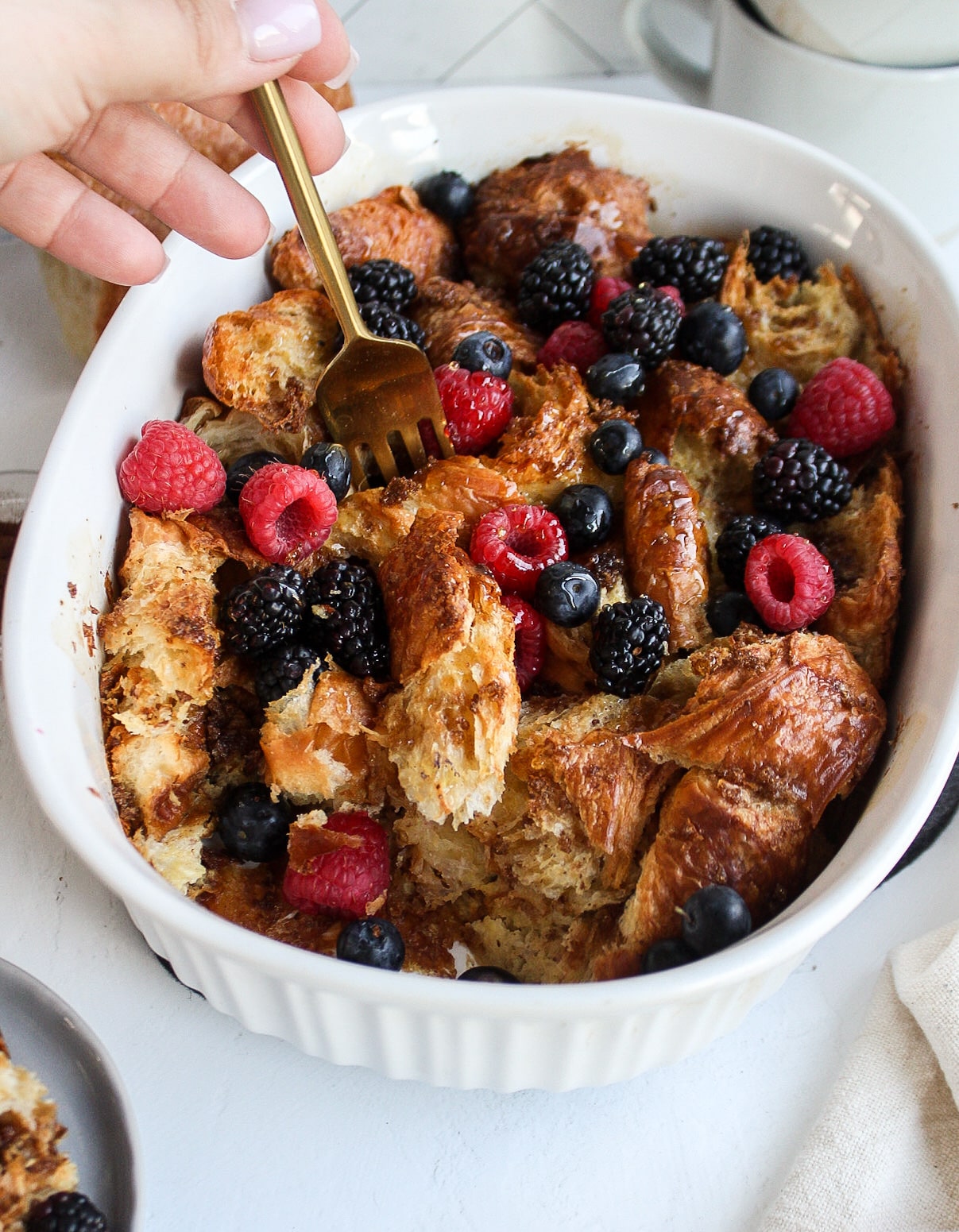 a fork taking a piece from the croissant french toast bake
