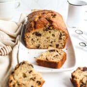 banana bread with honey and chocolate on a platter with a few piece scattered