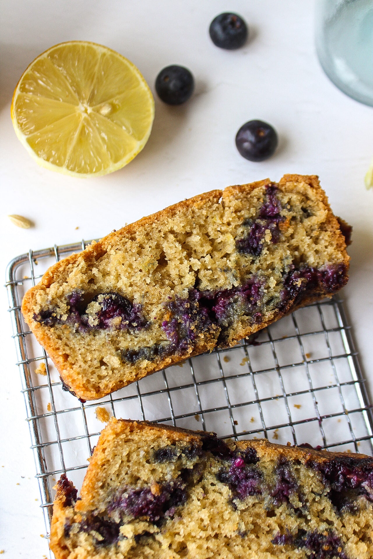 close up of a piece of lemon blueberry bread with blueberry and lemon surrounding it