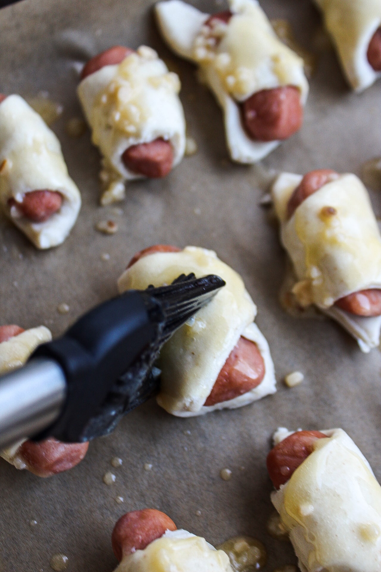 a basting brush topping off pigs in a blanket