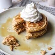 pancakes on a plate with syrup and whipped cream