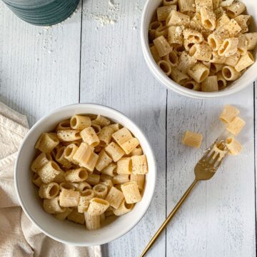 two bowls of parmesan pasta with pasta on a fork