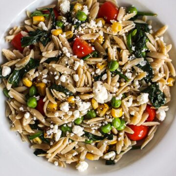 a bowl of orzo pasta with vegetables and cheese