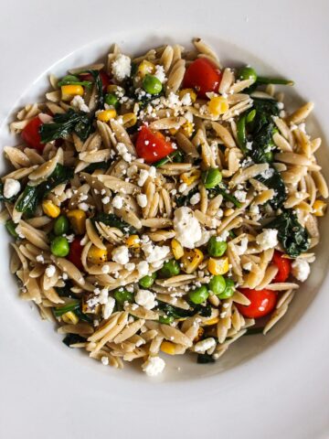 a bowl of orzo pasta with vegetables and cheese