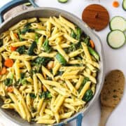 pasta and veggies in a pan with salt and a spoon around it