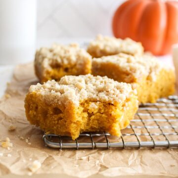 close up of a piece of pumpkin coffee cake with a pumpkin in the background