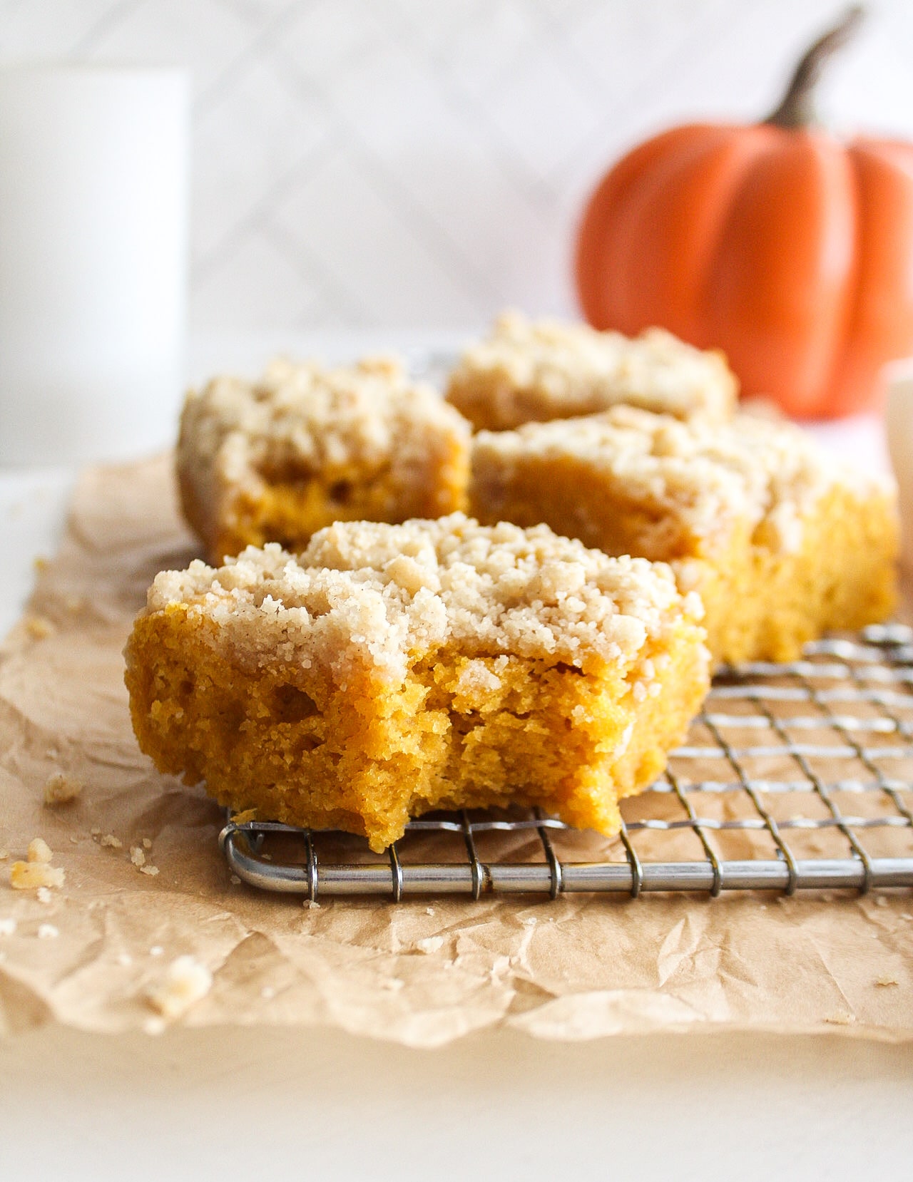 close up of a piece of pumpkin coffee cake with a pumpkin in the background