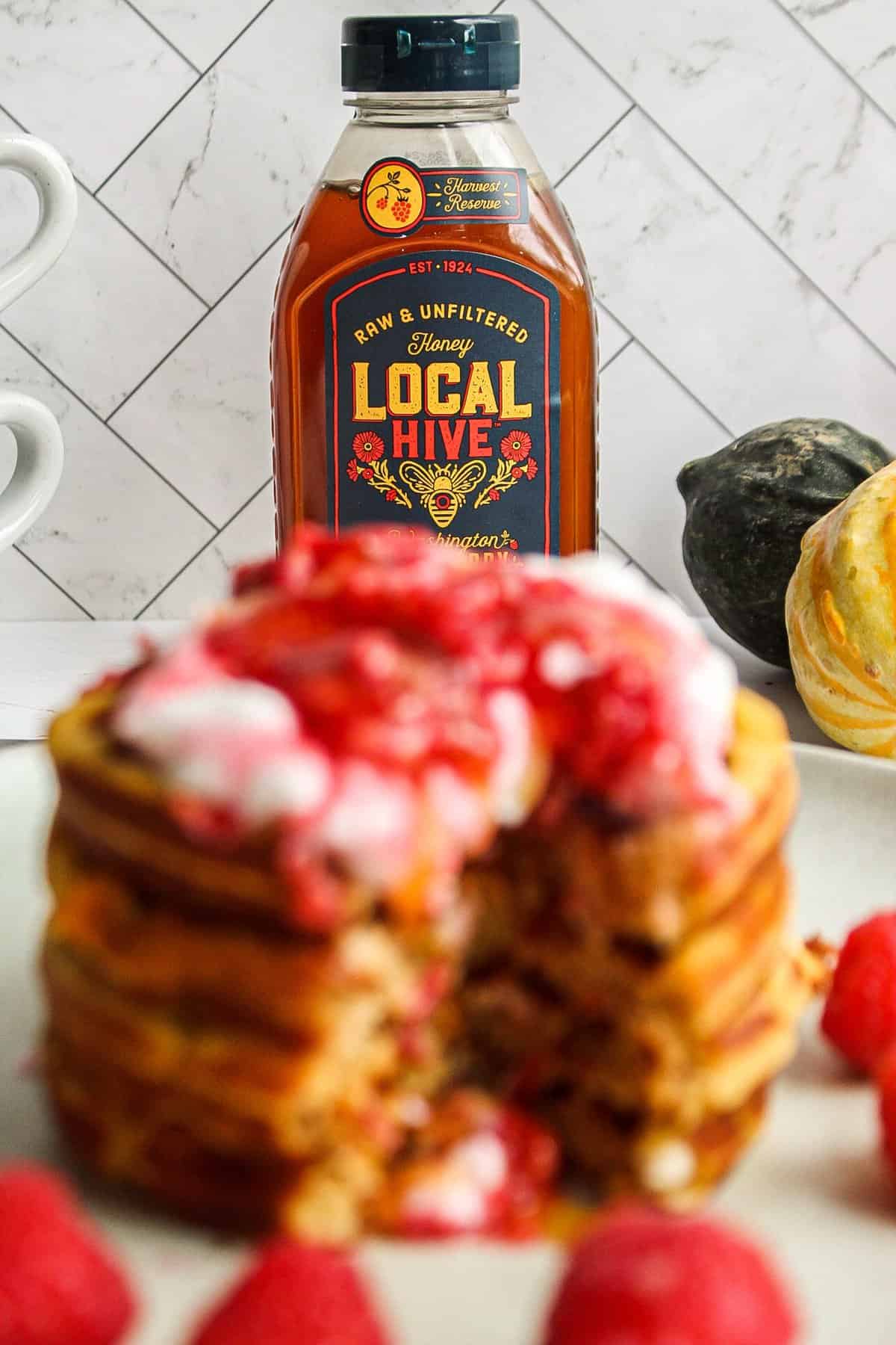 four pumpkin honey waffles stacked with whipped cream and honey