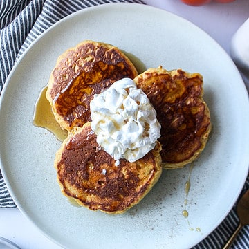 pumpkin pancakes on a plate with whipped cream