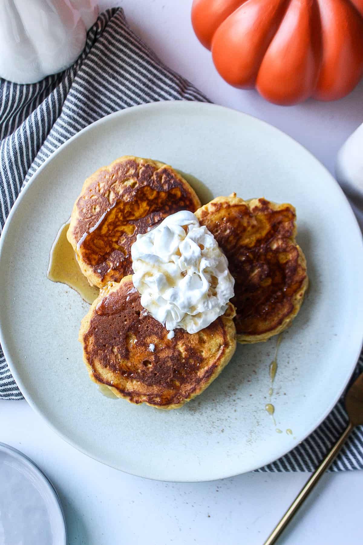 pumpkin pancakes on a plate with whipped cream