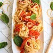 platter of swirled pasta with tomato and basil