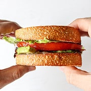a BLT with avocado held between two hands