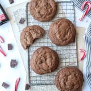 a few chocolate peppermint cookies surrounded by candy canes on a cooling rack