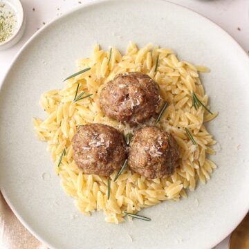 a few meatballs on a bed of orzo on a plate
