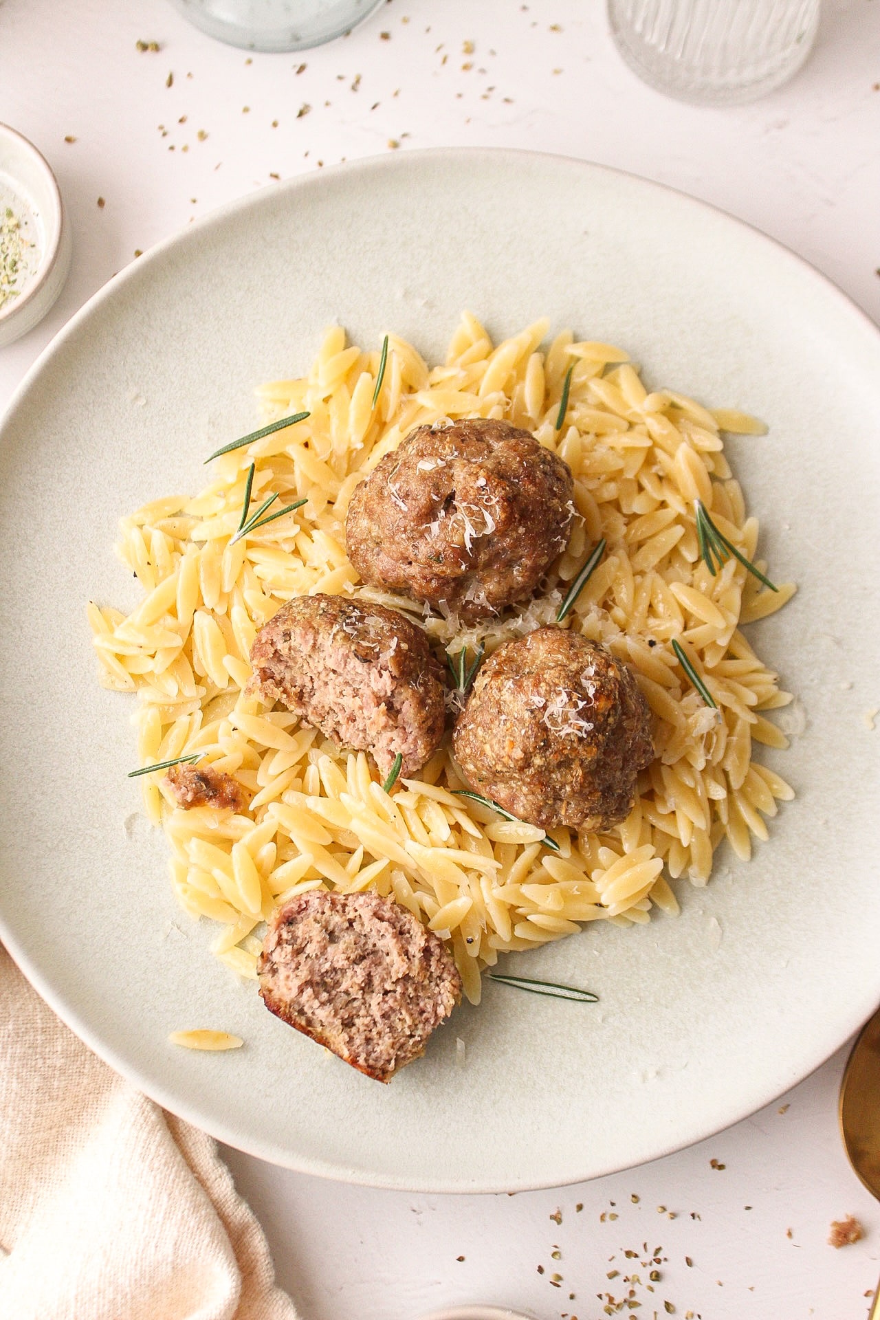 four meatballs on a bed a orzo with one of the meatballs cut open