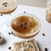 an espresso martini with a dusting of espresso powder and beans in a coupe glass