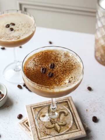 an espresso martini with a dusting of espresso powder and beans in a coupe glass
