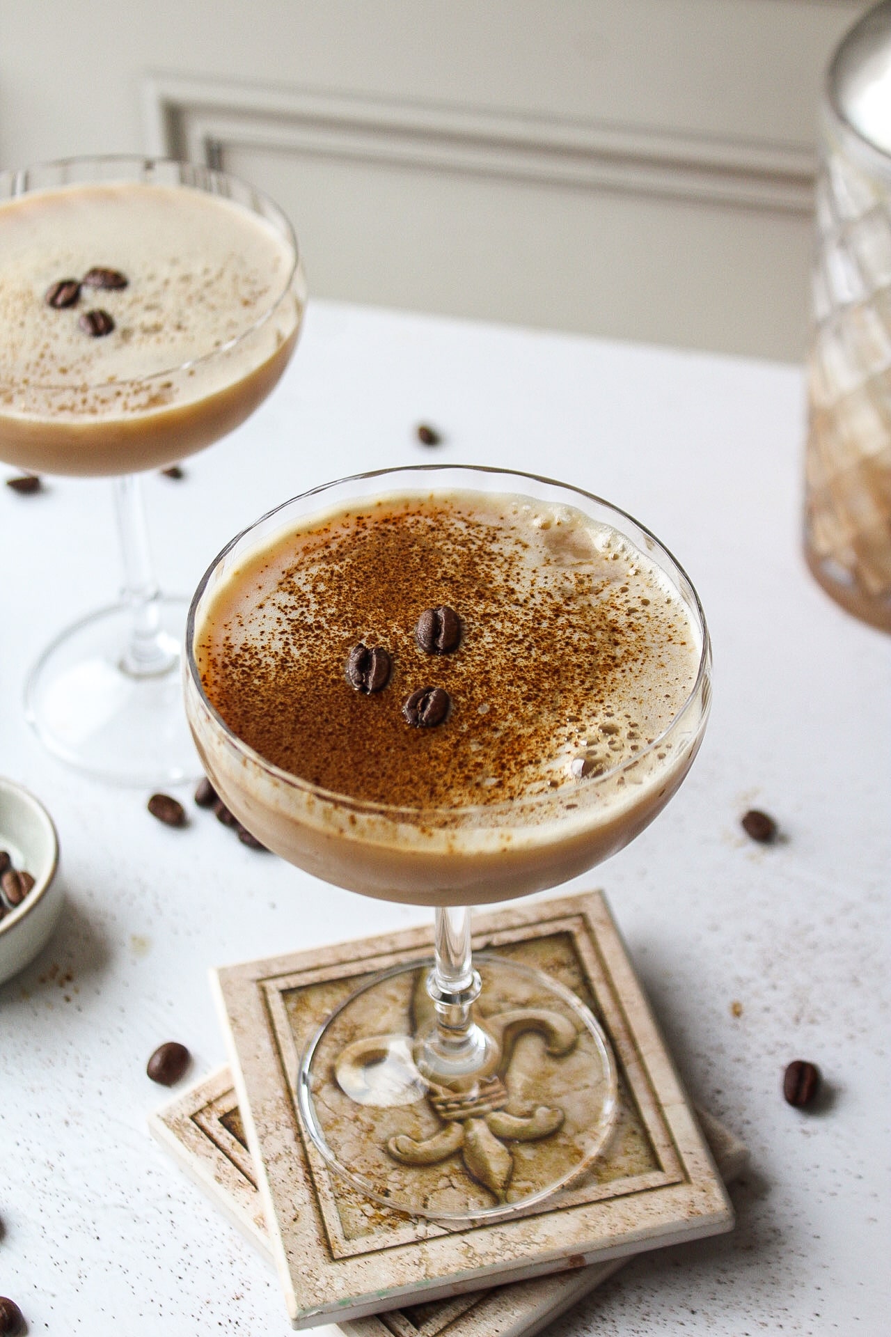 an espresso martini with a dusting of espresso powder and beans in a coupe glass