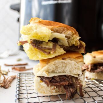 a stack of two pot roast sliders with a slow cooker in the background