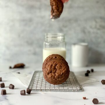 a cookie being dipped into a jar of milk with other cookies in front