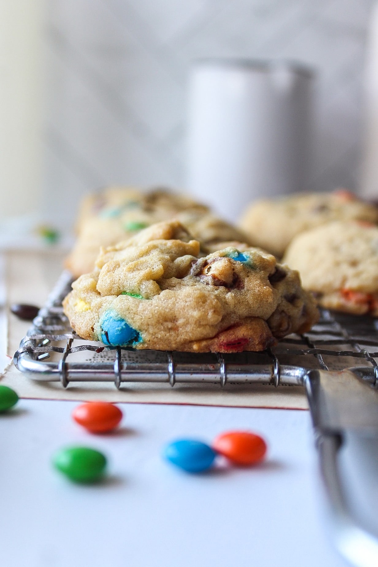 a close up of a cookie on a cooling rack with m&ms are around it