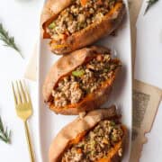 three sweet potatoes stuffed with ground turkey on a plate