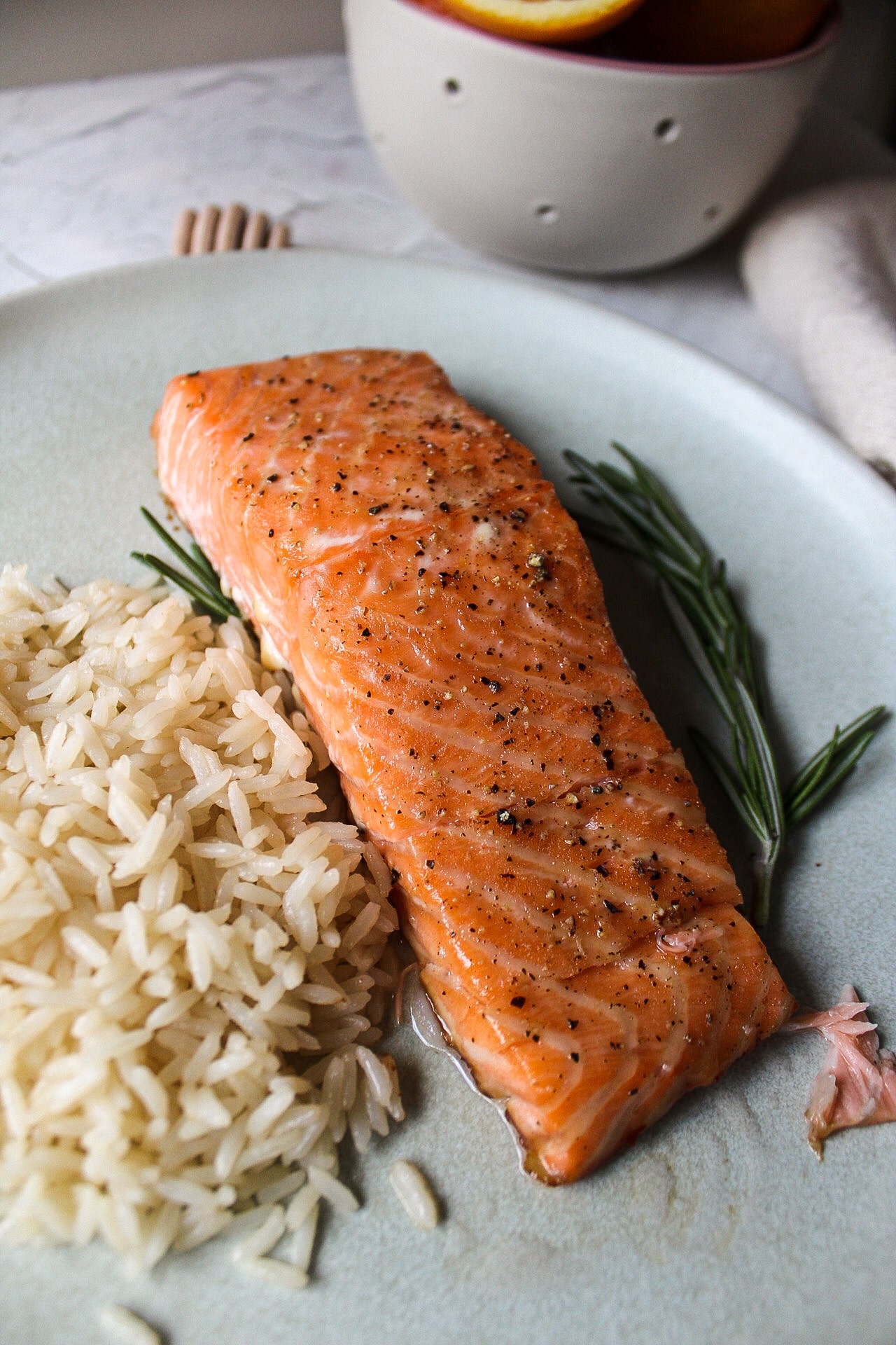 a filet of salmon with rice and rosemary on a plate