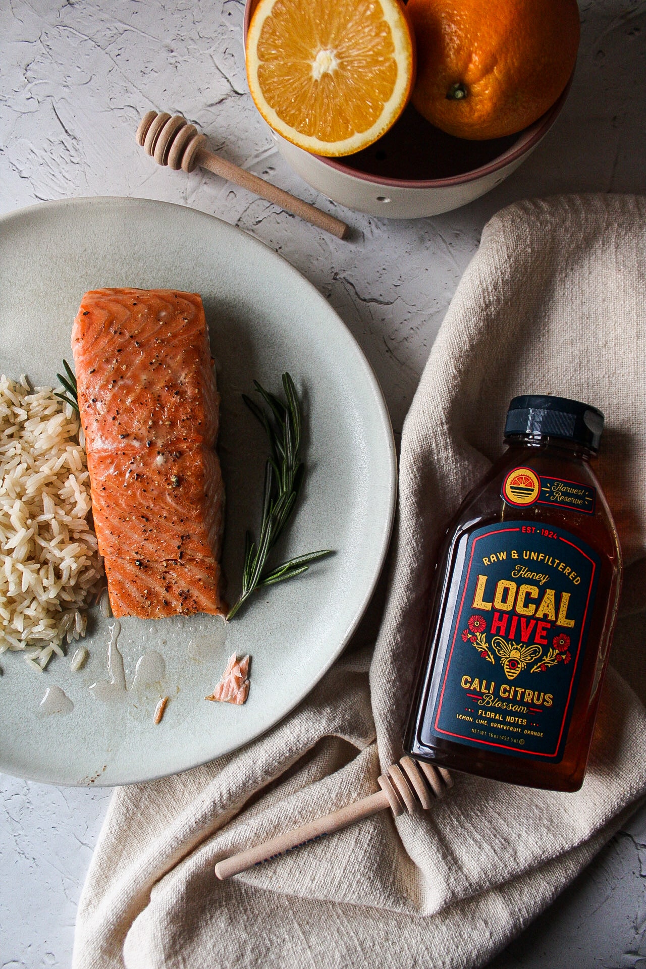 a plate of salmon with rice next to a bottle of honey